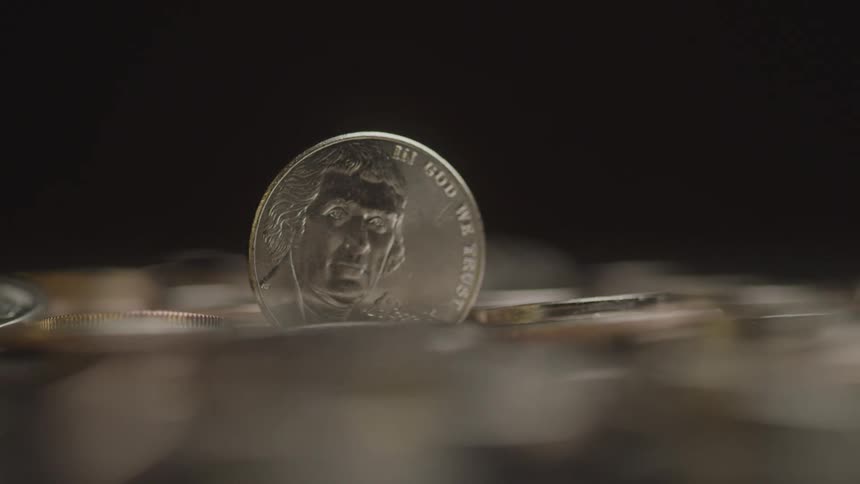 Close up of a coin placed vertically on a surface among other similar coins laying flat