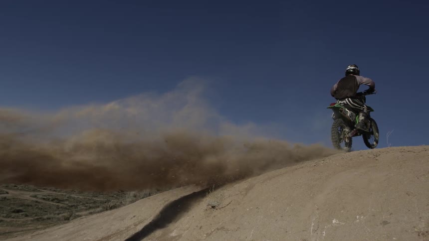 Dirt bike rider climbs dusty trail