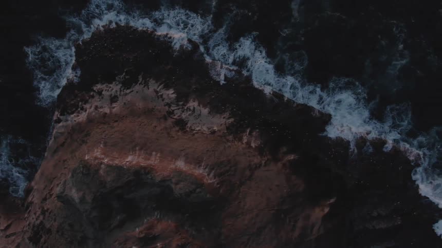 Aerial view of ocean waves crashing against a rocky coastline