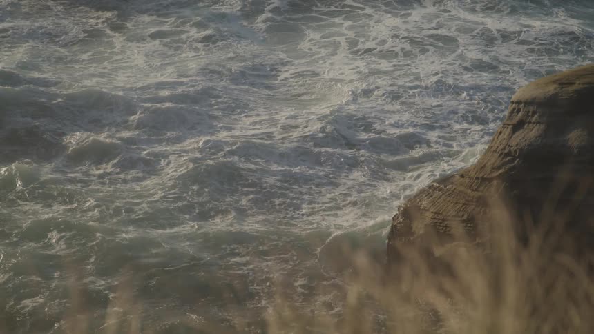 Rough waters crash against the rocks below