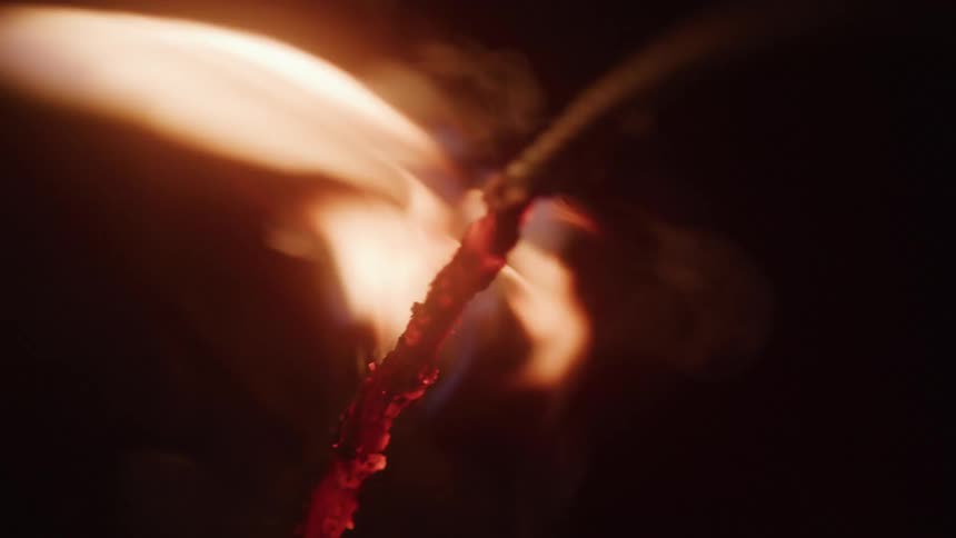 A bright sparking flame engulfs a fuse against a dark background