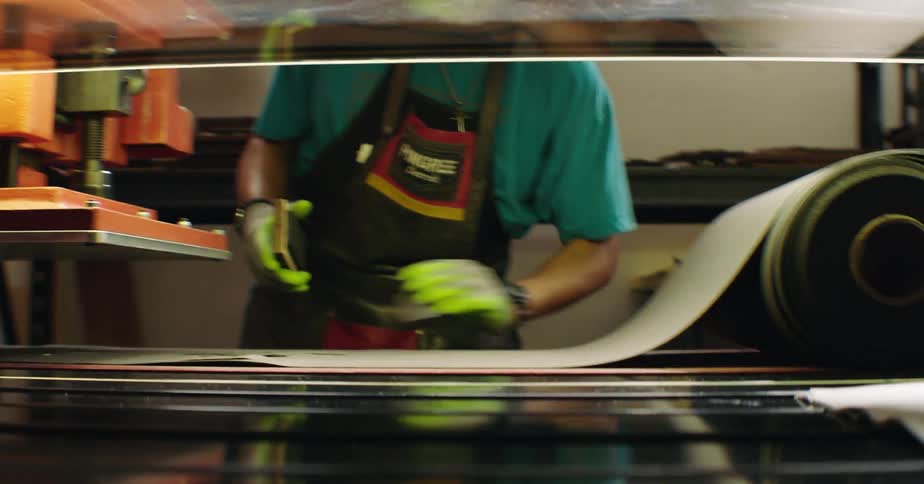 A craftsman cuts a piece of leather in a workshop