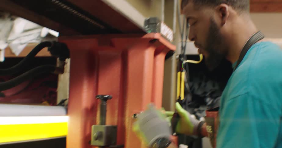 Man wearing gloves and apron working with machinery indoors