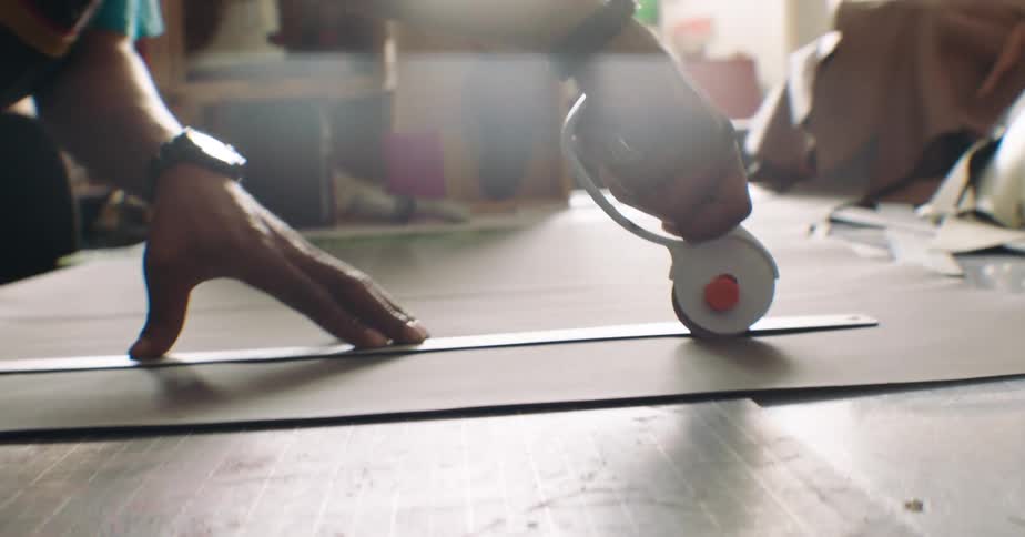 Hand with a roller and a ruler working on a fabric
