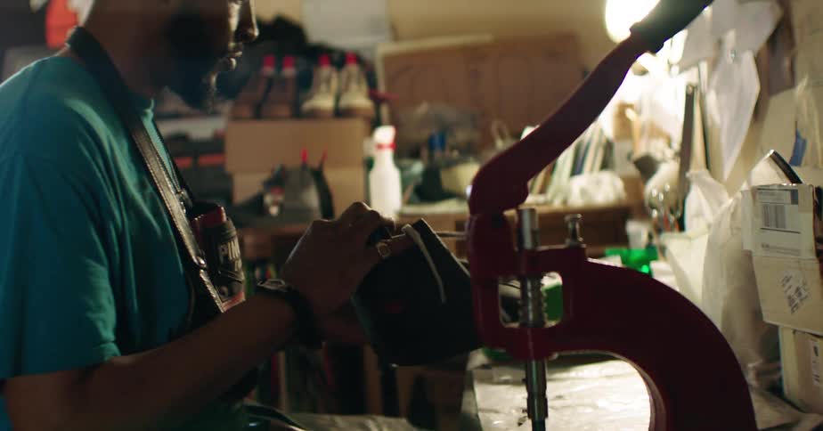 A shoemaker makes a shoe inside a workshop