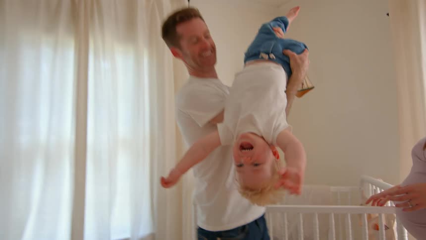 Father in a room playing with a son accompanied by his pregnant wife