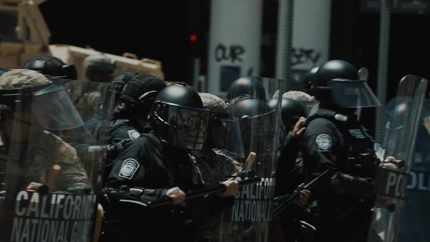 Police troops with shields and batons retreating on an urban road