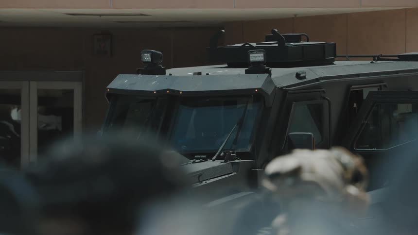 Officers in camouflage walk past the armored vehicle