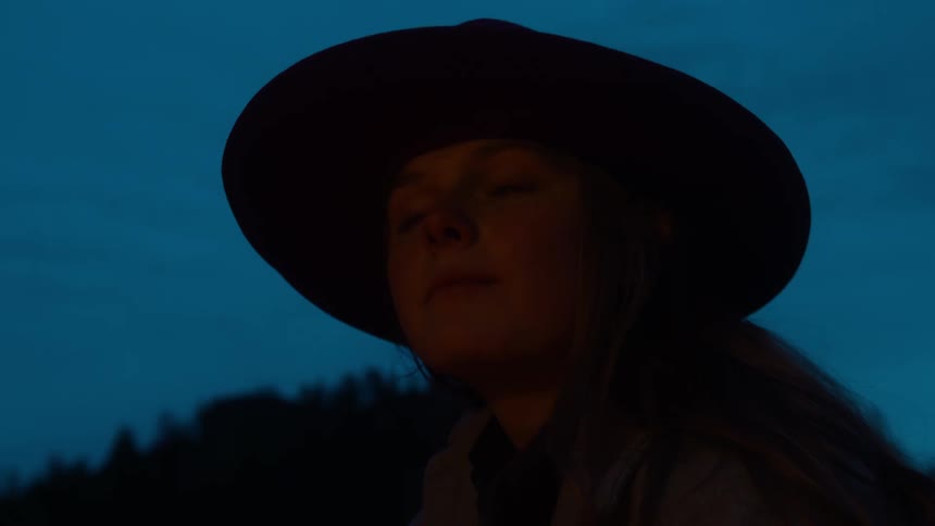 Firelight lights a womans face at night