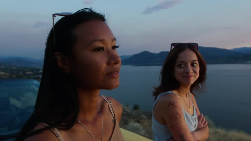 Two women in an elevated setting with happy expression and seaside