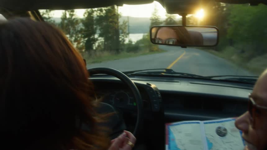 Two women looking at the map and traveling in the car on the road
