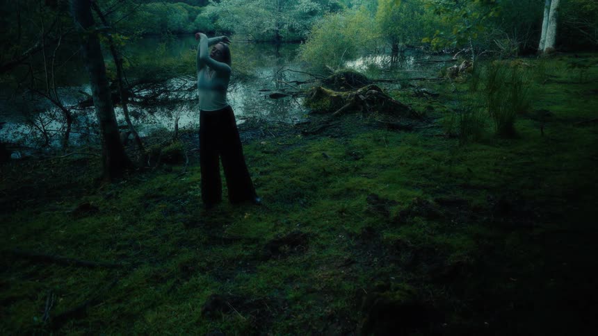 Woman making body movements in a swamp by a lake