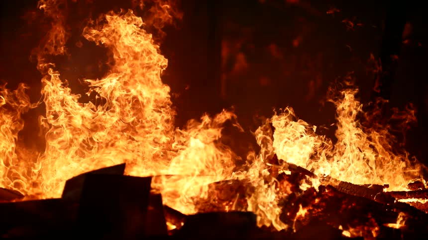 Fire burns through rubble at night