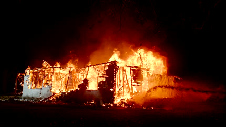 Completely destroyed house catches fire at night