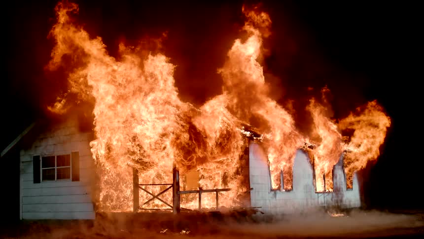 Flames glow and rise as a blazing fire engulfs a building