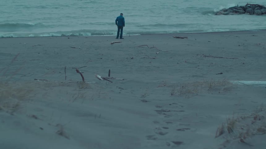 A man takes a picture of the water and then walks away