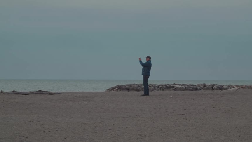 A man stand on the beach and take a pic