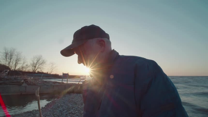 A man waves around a stick on the beach