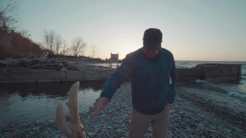 A man pulls at some driftwood on the beach