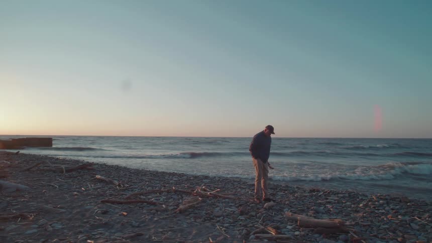 Man in cap walking on beach on cold morning