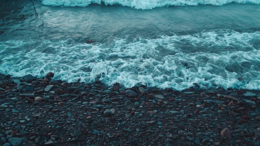 Waves splash as they roll in to shore and over the rocks along the coast