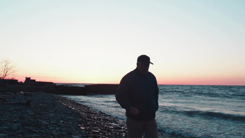 Man walking along the coast on the beach as waves roll in to shore