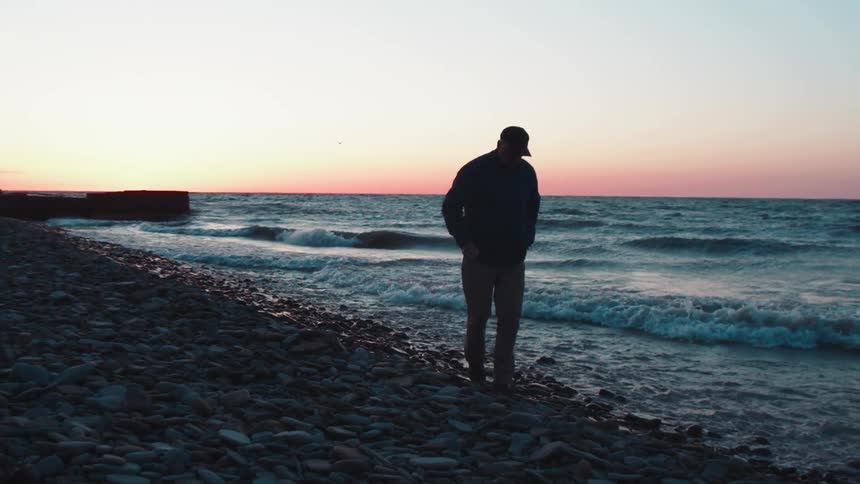 Man walking on rocks on a deserted beach on a winter dawn