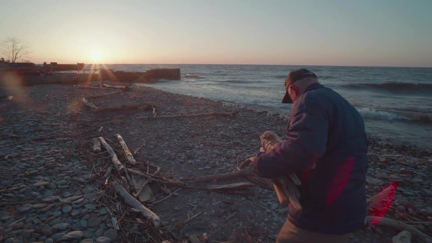 A man is collecting driftwood on the beach