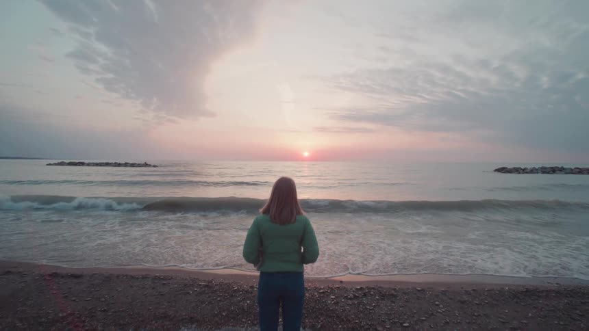 Woman on the sand of the beach at dawn