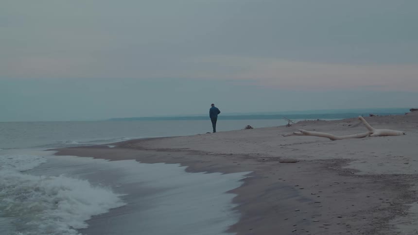 A man walks alone along a quiet empty beach
