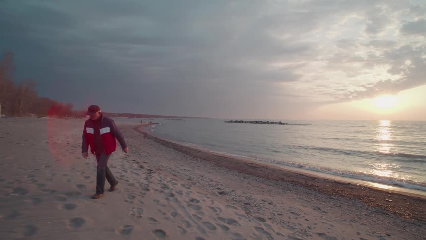 Man in cap walks on a beach