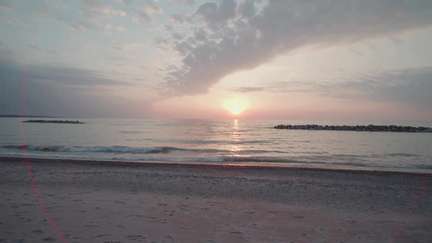 Ocean sunset over calm waves from a sandy beach