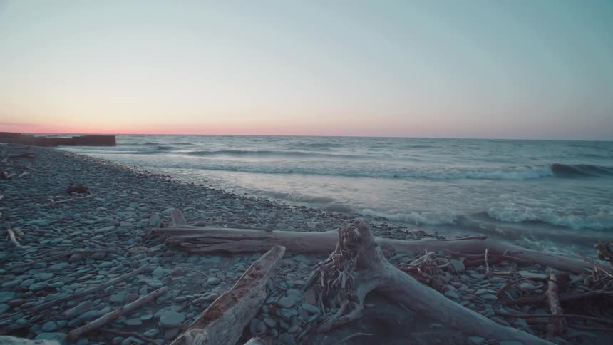 Waves hit a rocky beach as the sun sets
