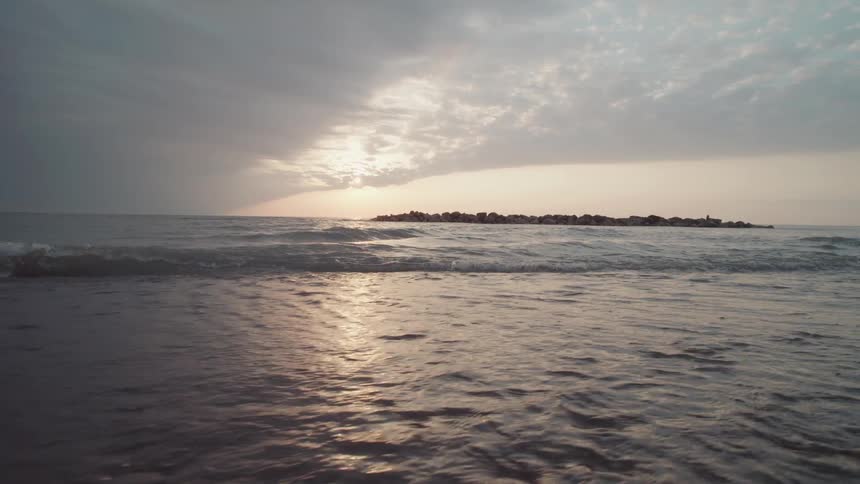 Ocean waves hit the shore at sunset