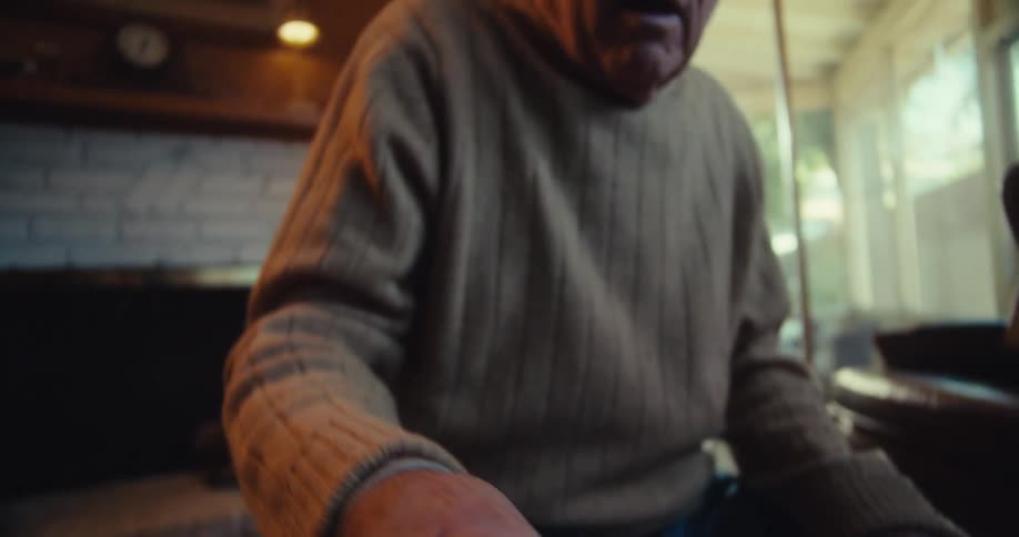 Elderly man sitting holding a device