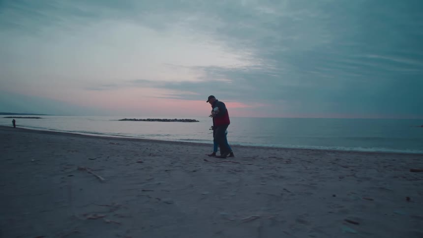 Two people walking on the beach at sunset