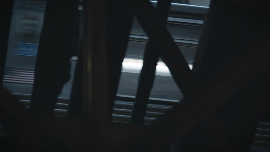 A train speeds overhead as it passes in front of the steel beams of the bridge.