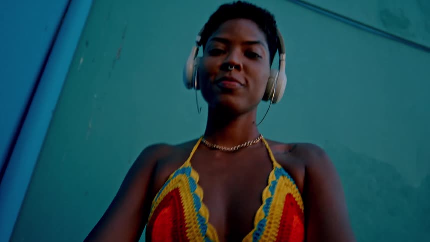 Woman in bikini and denim shorts with headphones dancing