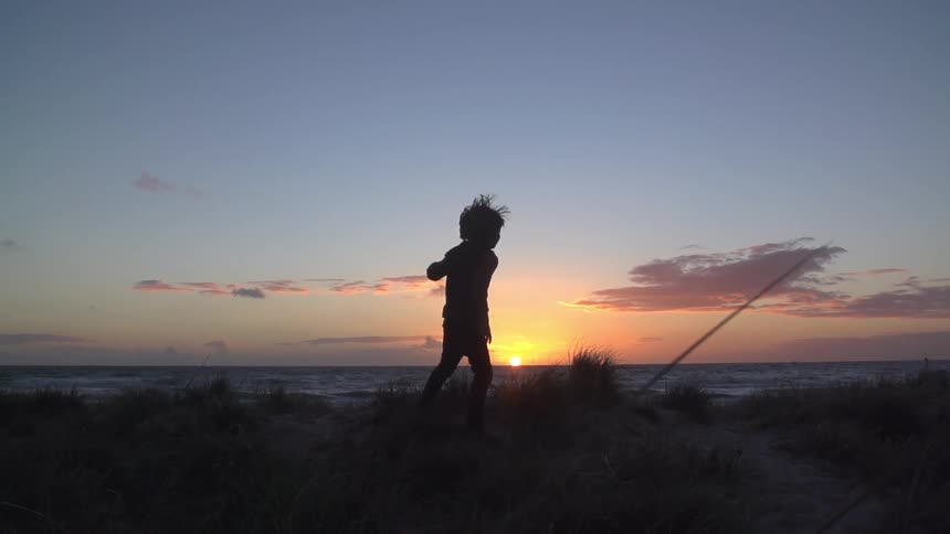 A kid playing during sunset