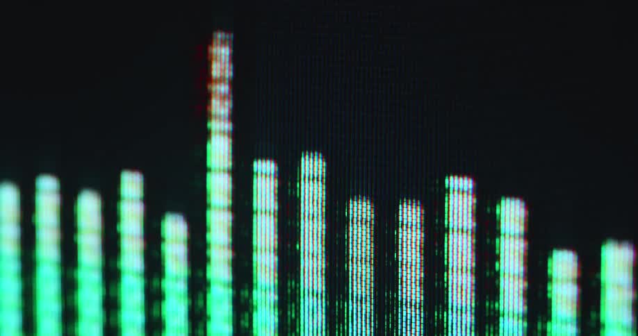 Extreme macro close-up of a green colored audio graph with red tips as a symbol for a loud song or noise with high frequencies as a sensory impression for the listener of the live music