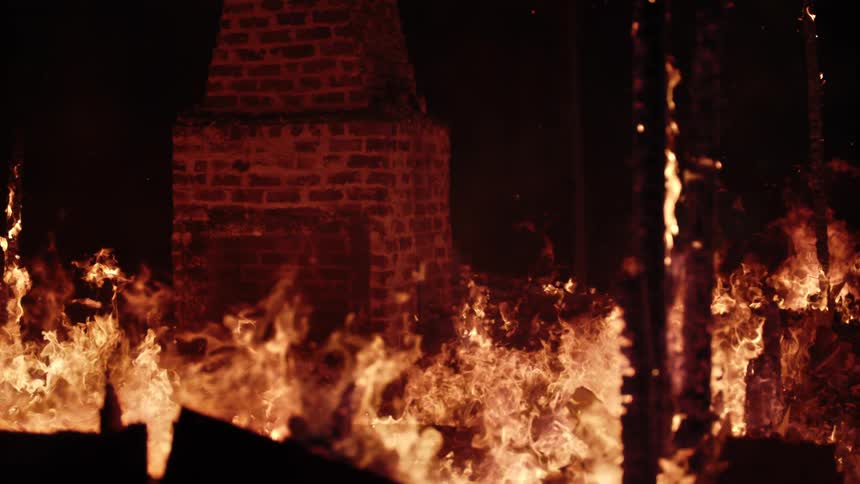 Brick fireplace surrounded by flames at night