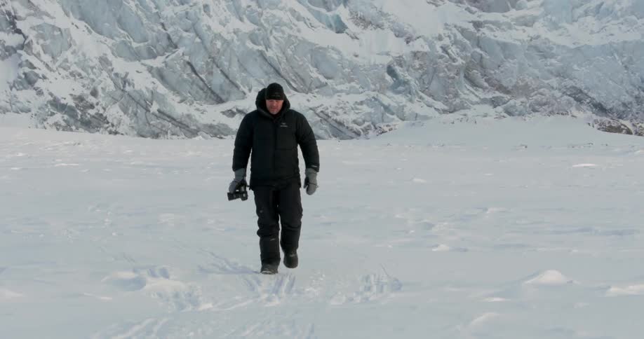 Man walking through the snow holding a camera