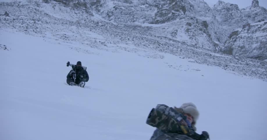 Two people are hiking down a snow covered hill one falls down
