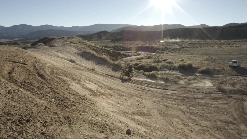 Person riding a dirt bike up and back down a dirt hill