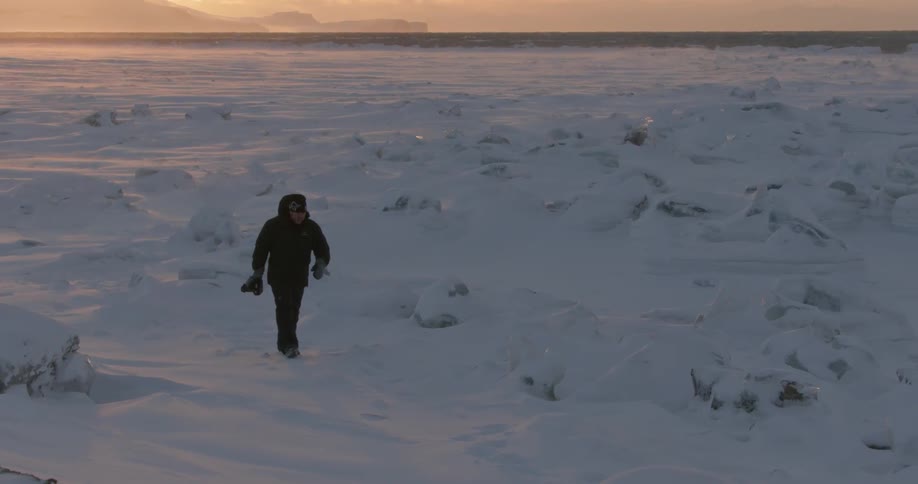Man with camera walking in snow covered arctic wilderness