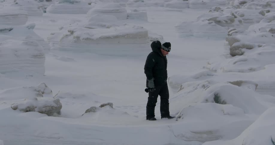 Man walking through the snow holding a camera