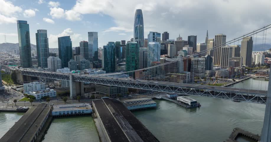 Aerial hyperlapse of San Francisco skyline with the large suspension Bay Bridge crossing a waterfront