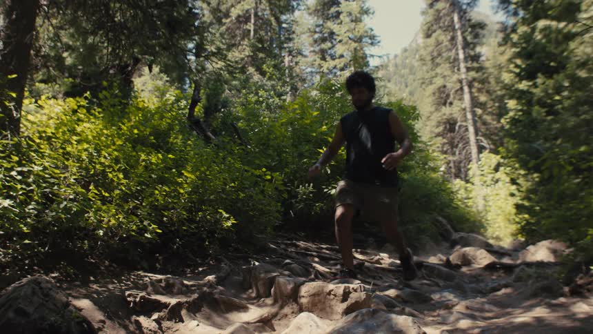 Man running along a rocky trail in the forest