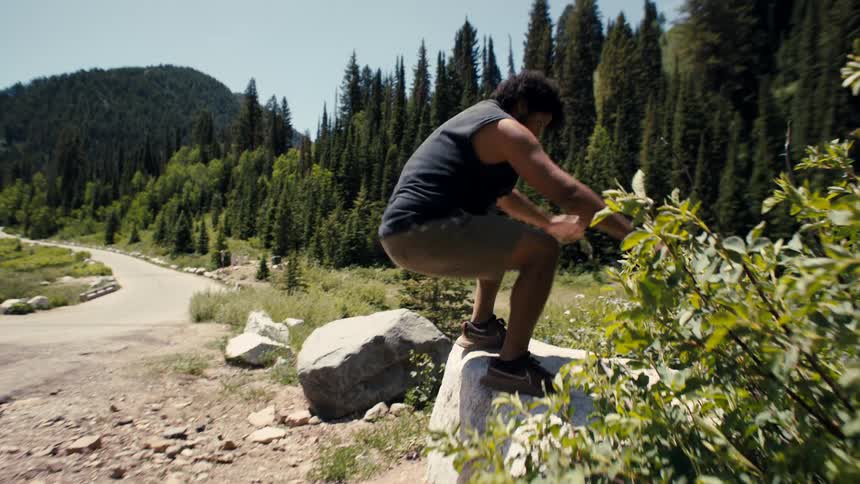 A man is repeatedly jumping on a boulder