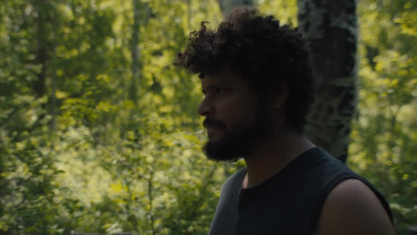 Curly haired man walking through a forest